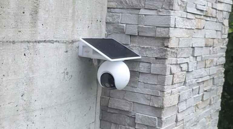 Solar-Akku-Überwachungskamera mit Solarpanel an einer Naturstein-Aussenwand