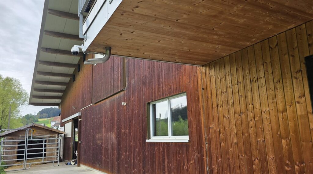 smart-cam Stall-Kamera unter dem Dachvorsprung eines Holzstalls