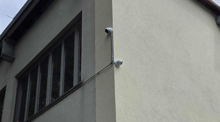 Hikvision Dome-Kamera hoch an verputzter Gebäudeecke mit Hinweisschild zur Videoüberwachung