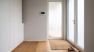Weisses Bedienteil einer Alarmanlage auf Schulterhoehe im Eingangsbereich eines modernen Wohnhauses
