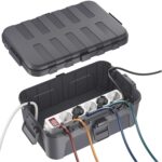 Geoeffnete dunkelgraue Kabelbox mit eingelegter Steckdosenleiste und herausgefuehrten Kabeln