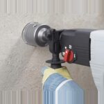 Bohrhammer mit Bohrkrone wird beidhaendig an der Wand gefuehrt
