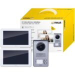 VIMAR K40915 Set mit weisser 7-Zoll-Touchscreen-Innenstation, grauem Klingeltableau mit Regenschutzrahmen und Netzteil mit Wechselsteckern.
