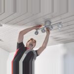 Elektriker montiert mit dem Schraubendreher eine Deckenleuchte