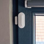 Weisser Safe2Home Funk-Magnetkontakt mit separatem Magnet und roter Melde-LED, montiert am Fensterflügel