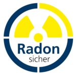 Eingebaute Mauerdurchführung von Ritzer mit Pressplatte aus Edelstahl in einer Kernbohrung, durch die ein schwarzes Rohr und zwei Kabel geführt sind