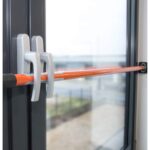 Orange Teleskop-Sicherungsstange von SCHMIDT security tools mit schwenkbaren gummierten Andruckplatten