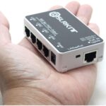Kompakter PoE-Passthrough-Switch von DSLRKIT mit schwarzer Deckelplatte und weissem Gehäuse, vier PoE-Ausgängen LAN1 bis LAN4, Uplink-Port, DC-Buchse und Schiebeschalter LAN/Ext