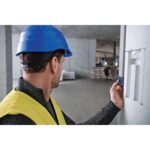 Schwarz-blauer Bosch Professional Laser-Entfernungsmesser GLM 50-23 G mit Farbdisplay, daneben Gürteltasche, Trageschlaufe und zwei AA-Batterien