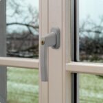 Silberner abschliessbarer ABUS-Fenstergriff FG210 in flacher, schlanker Bauform mit Druckzylinder und Wendeschlüssel