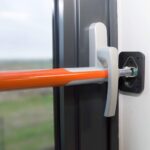 Orange Teleskop-Sicherungsstange von SCHMIDT security tools mit schwenkbaren gummierten Andruckplatten
